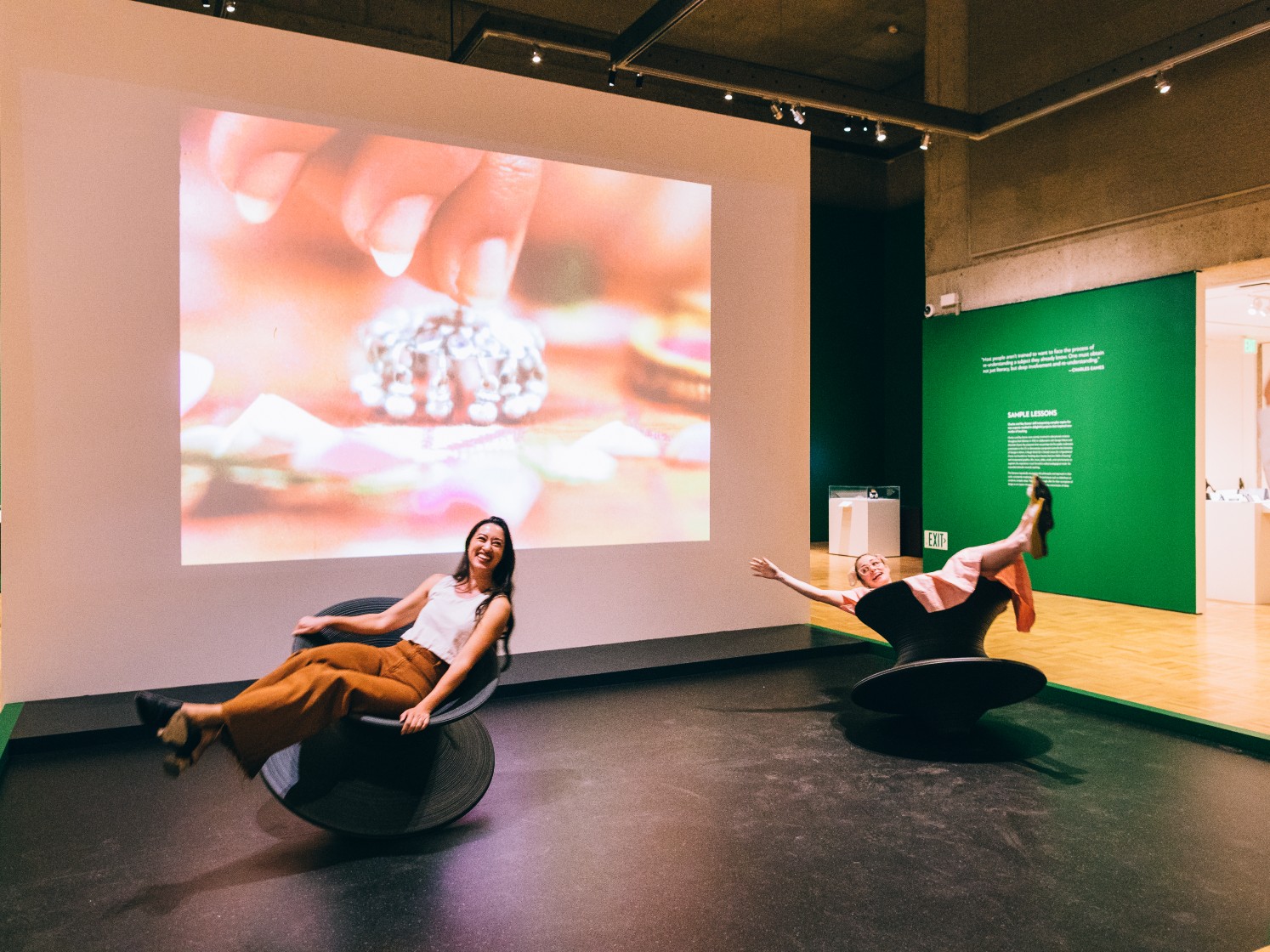 Erin Fong and Alexandra Bigley sit and spin in Magis Spun Chairs by Thomas Heatherwick as the Eames Tops film plays in the background. (Sothear Nuon)